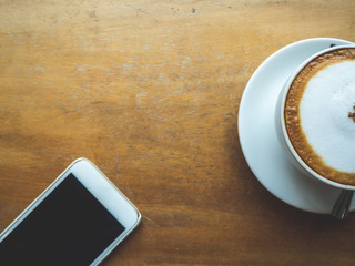 Coffee Time. Cappuccino with smartphone. on Wooden table in coffee shop. Cup of coffee in coffee shop. Empty cup of coffee.