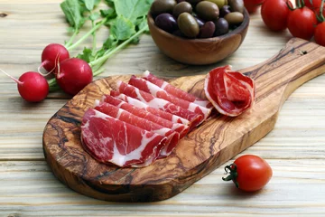 Poster antipasto carne di porco salata su tagliere di legno sfondo tavolo di cucina © denio109