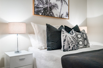 Modern home interior with bedroom setting including many pillows, and bedsides table with lamps.