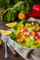 bowl of fresh salad with vegetables and greens on wooden table
