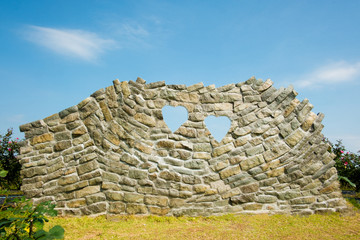 Rock wall with heart shape and  blue sky view, grunge wall