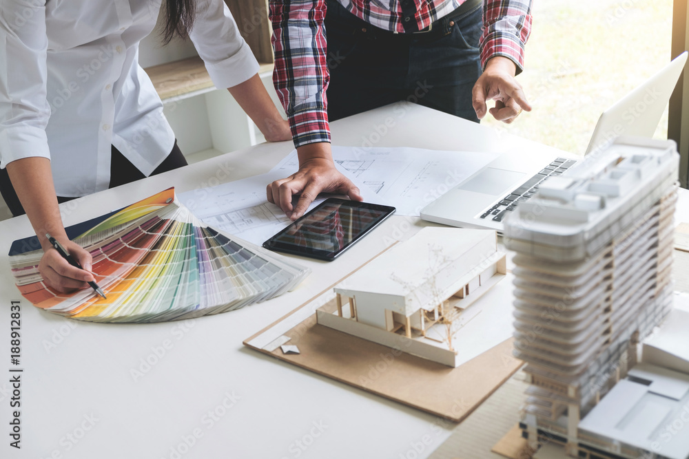 Poster Two interior design or graphic designer at work on project of architecture drawing with work tools and color swatches, colour chart, color samples for selection, renovation and technology concept