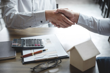 Real estate broker agent and customer shaking hands after signing contract documents for realty purchase, Bank employees congratulate, Concept mortgage loan approval