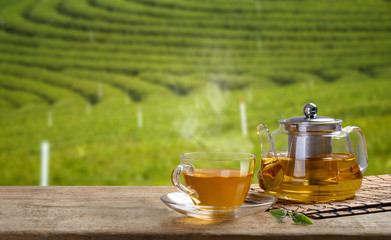 Tea cup and glass jugs or jars. with and tea leaf sacking on the wooden table and the tea plantations background