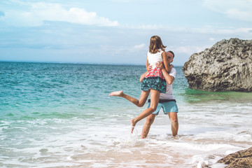 Naklejka premium Happy young honeymoon couple having fun on the beach. Ocean, tropical vacation on Bali island, Indonesia.
