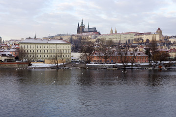 Fototapeta premium Snowy Prague Lesser Town with gothic Castle above River Vltava, Czech republic