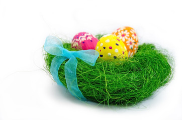 Easter eggs in nest from grass with a bow on white background