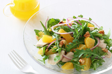 Summer salad with arugula, boiled chicken breast, red onion, and orange 