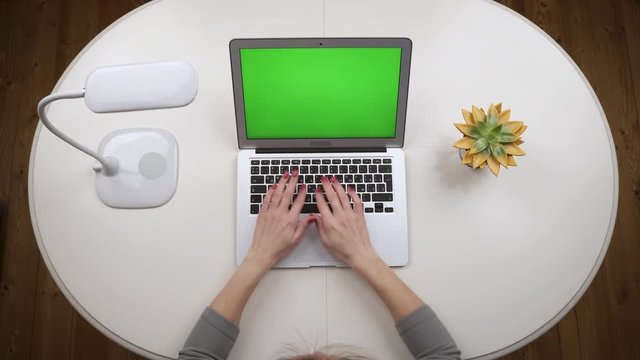 Woman opens a laptop, standing on the white table with lamp, typing text and closing a laptop. Top view. Hands close up