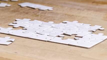 a puzzle to be completed, white jigsaw/puzzle to be completed , over wooden table background,...