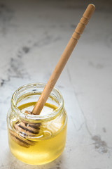 Honey in jar with wooden stick on a table