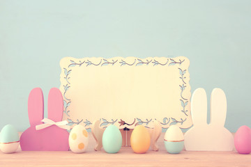 Cute colorful wooden bunny ears and easter eggs over wooden table.