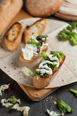 sandwiches with fresh herbs, sour cream and cheese and bread on a dark background