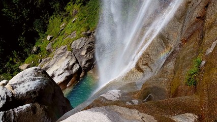 Rainbow of the small mountain waterfall , big rocks, perfectly clean water and spring green grass
