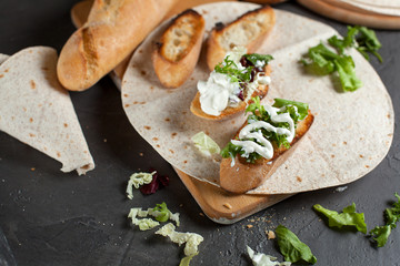 sandwiches with fresh herbs, sour cream and cheese and bread on a dark background