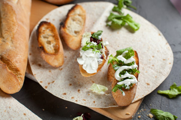 sandwiches with fresh herbs, sour cream and cheese and bread on a dark background