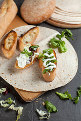 sandwiches with fresh herbs, sour cream and cheese and bread on a dark background