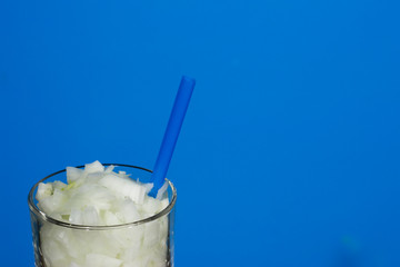 Glass with straw and chopped onion in pieces.