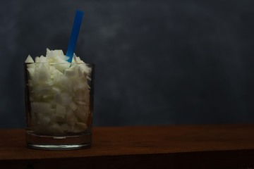 Glass with straw and chopped onion in pieces.