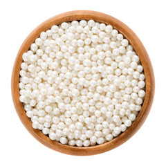 White nonpareils in wooden bowl. Hundreds and thousands. Decorative confectionery of tiny balls,...