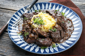 Fresh veal liver ragout in red wine sauce with mashed potatoes as close-up on a plate