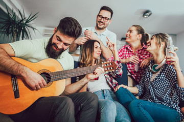 Group of happy young friends having fun and drinking beer in home interior