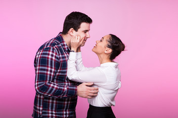 Fototapeta premium Woman playing and beeing silly with her husband in studio on pink background