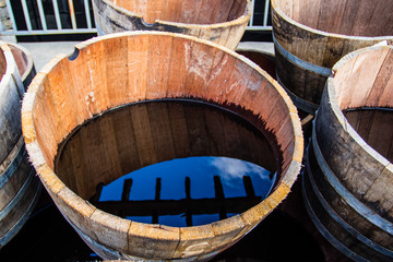 Old half barrels filled with water reflecting the surroundings.