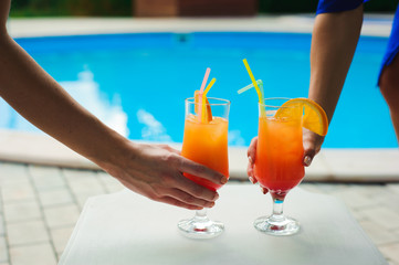 Bikini women in pool relaxing with juice, young beautiful sexy girls resting in vacation on summer season at swimming pool
