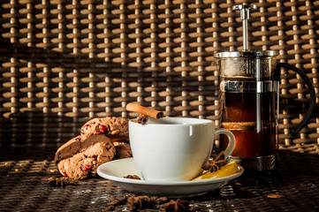 A cup of tea in the background with a biscuit and a tea pot