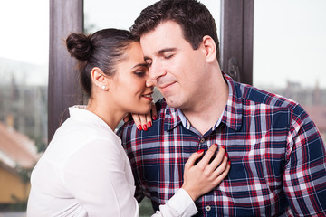 Fototapeta premium Close up image of couple sitting together next to a big window. Love and happiness