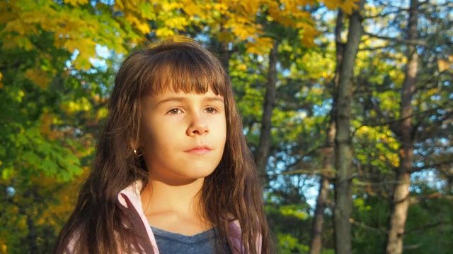 Portrait of a child. Sad little girl in an autumn park.