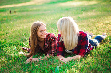 Two happy female friends playing and having fun in green grass