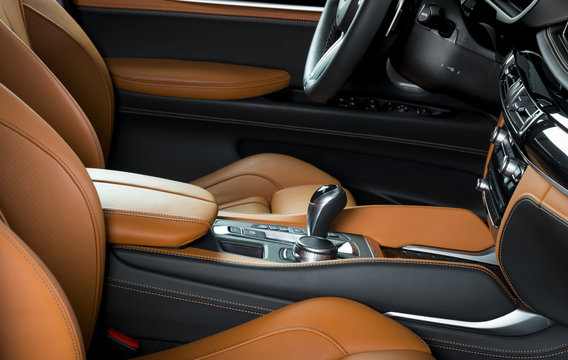 Modern luxury car Interior - steering wheel, shift lever and dashboard. Car interior luxury. Beige comfortable seats, steering wheel, dashboard, speedometer, display. Orange perforated leather.