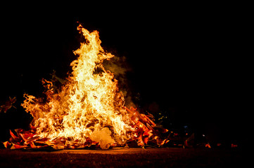 Crest of flame on burning wood in fireplace. Great ritual bonfire on a black background