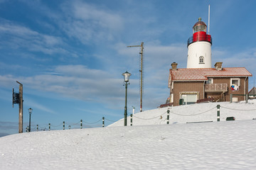 Dutch winter with snow and view at lighthouse of fishing village Urk