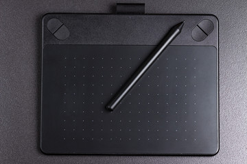 graphic tablet with pen on black background top view.