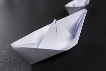 Paper boat close-up on black background. Origami ship paves the way