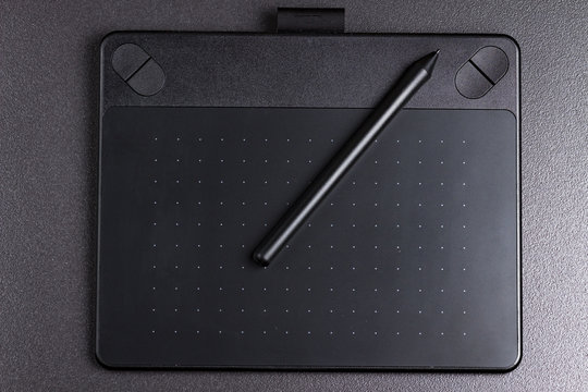 graphic tablet with pen on black background top view.