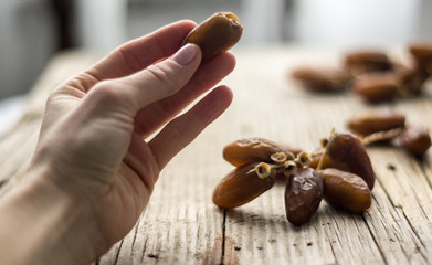 Dried dates hold by a woman, dated in the background on the wooden table