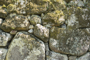 Stone wall background texture with green moss in traditional Japanese park in Kyoto, Japan. Nature stone background.