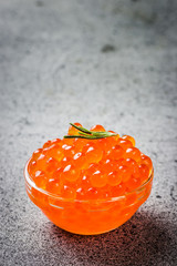 Red caviar on dark concrete background. Selective focus, space for text. 