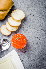 Red caviar, better, slices of bread on dark concrete background. Top view, space for text.
