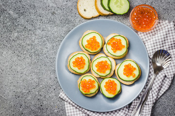 Caviar cucumber bites on concrete background. Top view, space for text.
