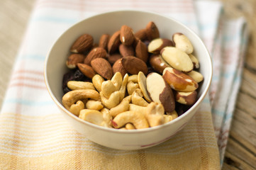 Little bowl of. mixed nuts (almonds, cashews and Brazil nuts) on the wooden table