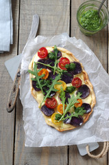 Flammkuchen mit blauen Kartoffeln, bunten Tomaten, Rucola und Rucolapesto