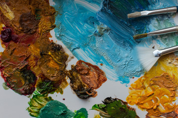 Close-up of artist brushes and colored paints on a white palette