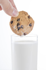 A chocolate cookie being dunked in a glass of milk. And white background. Studio shot.
