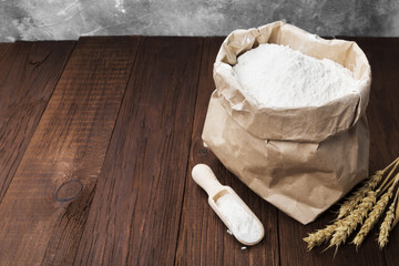 Paper package of wheat flour on a wooden background. Copy space. Food background