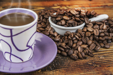 Cup od coffe with roasted bean on the wooden table.